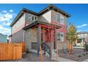 Two-story home with gray and red siding, a covered porch, and a fenced yard at 21124 E 63Rd Dr, Aurora, CO 80019