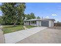 Newly painted Ranch home with a spacious driveway and mature tree in front at 1580 S Estes St, Lakewood, CO 80232