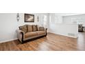 Living room with hardwood floors, neutral walls, and a brown couch at 1436 S Ensenada St, Aurora, CO 80017