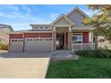 Two-story home with a red exterior, three-car garage, and front porch at 1178 Freedom Way, Castle Rock, CO 80109