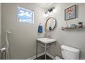 Stylish powder room with a floating vanity and round mirror at 6747 Raritan Dr, Denver, CO 80221