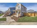 Two-story gray house with orange door, wooden fence, and small front yard at 10291 E 62Nd Pl, Denver, CO 80238