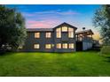 Two-story house with large windows, deck, and landscaped yard at dusk at 2203 S County Road 185, Byers, CO 80103