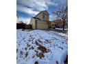 Two-story yellow house with a snow-covered lawn and landscaping at 21620 E Crestline Ln, Centennial, CO 80015