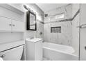 Updated bathroom with a white bathtub and marble-style tile at 5960 Rose Ln, Commerce City, CO 80022