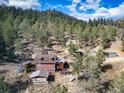 Aerial view of a house and surrounding land, showcasing the property's wooded setting and outbuildings at 18101 S Buffalo Creek Rd, Conifer, CO 80433