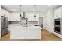 Modern white kitchen with island, stainless steel appliances, and herringbone backsplash at 42962 Colonial Trl, Elizabeth, CO 80107