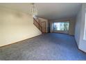 Living room with grey carpet, staircase, and window overlooking the backyard at 20420 Kelly Pl, Denver, CO 80249