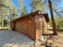 Attached two-car garage with wood siding and a spacious driveway at 8782 S Ault Ln, Morrison, CO 80465