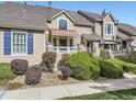 Tan two-story townhome with red door, landscaping, and walkway at 6220 Salvia St, Arvada, CO 80403