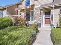 Tan two-story townhome with red door, striped awning, and landscaping at 6220 Salvia St, Arvada, CO 80403