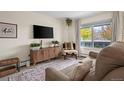 Living room features a brown couch, wooden cabinet, and large window at 1111 Elysian Field Dr # D, Lafayette, CO 80026