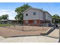 Two-story duplex with brick and siding, fenced yard at 4463 Adams St, Denver, CO 80216