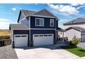 Two-story blue house with white two-car garage and landscaping at 45780 Silverdrop Ave, Bennett, CO 80102