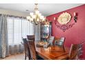 Dining room with wooden table, chandelier, and red accent wall at 21465 E 55Th Ave, Denver, CO 80249