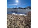 Partially snow covered backyard with a wooden fence at 5046 Espana Way, Denver, CO 80249
