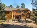 Two-story home with wood siding, stone accents, and a yard at 28730 Mountain View Rd, Conifer, CO 80433
