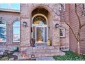 Brick front entrance with arched entryway and welcoming landscaping at 4756 E Pinewood Cir, Centennial, CO 80121