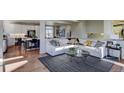 Bright living room with hardwood floors, white sectional sofa and a view of the kitchen at 1230 Sugarloaf Ln, Erie, CO 80516