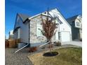 Two-story home with stone and white siding, landscaped yard, and a two-car garage at 16487 E 111Th Pl, Commerce City, CO 80022