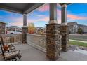 Covered front porch with stone pillars and white railing at 23890 E Minnow Dr, Aurora, CO 80016