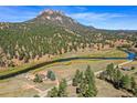 Aerial view showcasing house, river, and mountain backdrop at 2677 S Platte River Rd, Sedalia, CO 80135