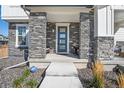 Covered front porch with stone columns and a blue front door at 21208 E 63Rd Ave, Aurora, CO 80019