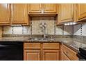 Kitchen features granite countertops, oak cabinets, and decorative tile backsplash at 585 S Alton Way # 4D, Denver, CO 80247