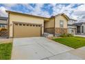 Tan single-story house with a two-car garage and manicured lawn at 9804 Truckee St, Commerce City, CO 80022