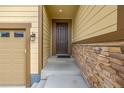 Front entry with dark brown door and stone accents at 9804 Truckee St, Commerce City, CO 80022