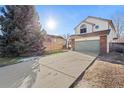 Two-story house with a large driveway and mature tree at 1749 Foster Dr, Longmont, CO 80501