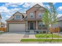 Two-story house with brown siding, gray garage door, and landscaped front yard at 954 Plum Creek Ct, Brighton, CO 80601