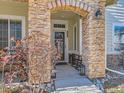 Stone-accented entryway with arched alcove, rocking chairs, and landscaping at 199 Whitehaven Cir, Highlands Ranch, CO 80129