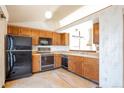 Galley-style kitchen with wood cabinets and black appliances at 6024 S Taft Way, Littleton, CO 80127