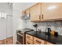 Modern kitchen with light wood cabinets,hexagon backsplash, and dark countertops at 444 17Th St # 205, Denver, CO 80202