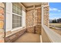 Small covered porch with stone wall and white railing at 12740 Jasmine St # E, Thornton, CO 80602