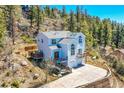Stunning aerial view of a two-story house with a deck, hot tub, and mountain backdrop at 11770 Leavenworth Dr, Conifer, CO 80433