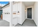 Welcoming front porch with a black front door, modern light fixtures, and an attached garage at 1562 Farmstead St, Brighton, CO 80601