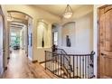 Elegant hallway with hardwood floors, curved staircase, and arched doorways at 7818 Vallagio Ln, Englewood, CO 80112