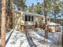 Two-story house exterior, brick and siding, snowy yard, and attached garage in wooded area at 720 Arapahoe Dr, Monument, CO 80132