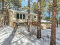 Two-story house exterior nestled among tall pine trees in a snowy setting at 720 Arapahoe Dr, Monument, CO 80132