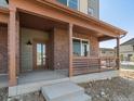 Front porch with brick columns and wood railing at 13804 Vispo Way, Broomfield, CO 80020