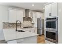 Image of a modern kitchen with white cabinets, stainless steel appliances, and herringbone backsplash at 42982 Colonial Trl, Elizabeth, CO 80107