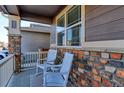 Charming front porch with rocking chairs and brick accents at 9299 Rifle St, Commerce City, CO 80022