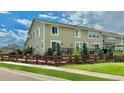Tan two-story house with a wooden fence and small trees at 14595 Vancouver Pl, Parker, CO 80134