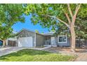 Ranch-style home with gray siding, white garage door, and mature trees at 8320 Currant Way, Parker, CO 80134