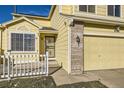 Front entrance of a yellow house with a white picket fence and a brick accent at 20937 Kelly Pl, Denver, CO 80249