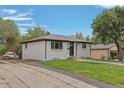 White ranch home with driveway, landscaping, and detached garage at 7946 Joan Dr, Denver, CO 80221
