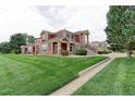 Two-story townhome with red exterior and manicured lawn at 13722 Legend Way # 101, Broomfield, CO 80023