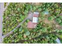 Aerial view of a house nestled in a wooded area with a driveway and detached garage at 9248 Black Mountain Dr, Conifer, CO 80433